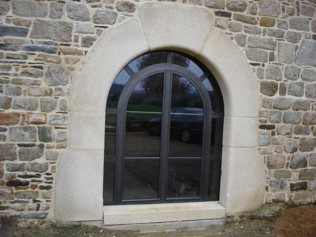 Fenêtre aluminium Arabesk cintrée (plein cintre) anthracite dans un mur en pierre