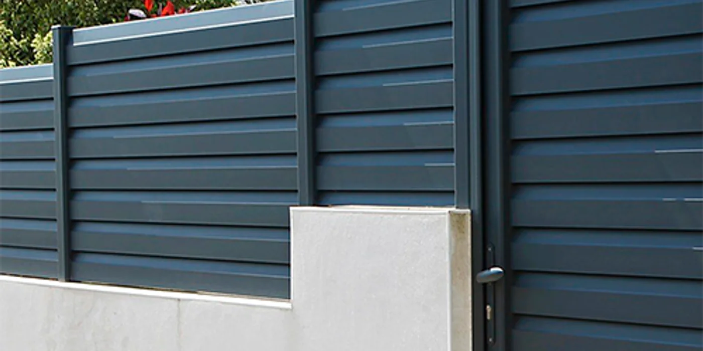 Clôture rigide en panneaux soudés gris installée le long d'un jardin