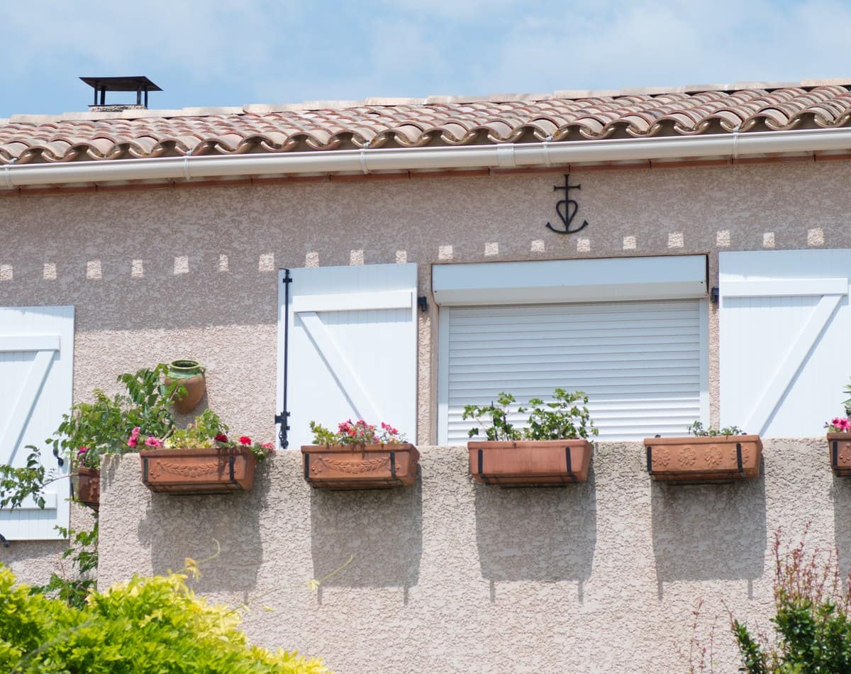 Volets battants PVC blancs KparK centrés sur une façade provençale